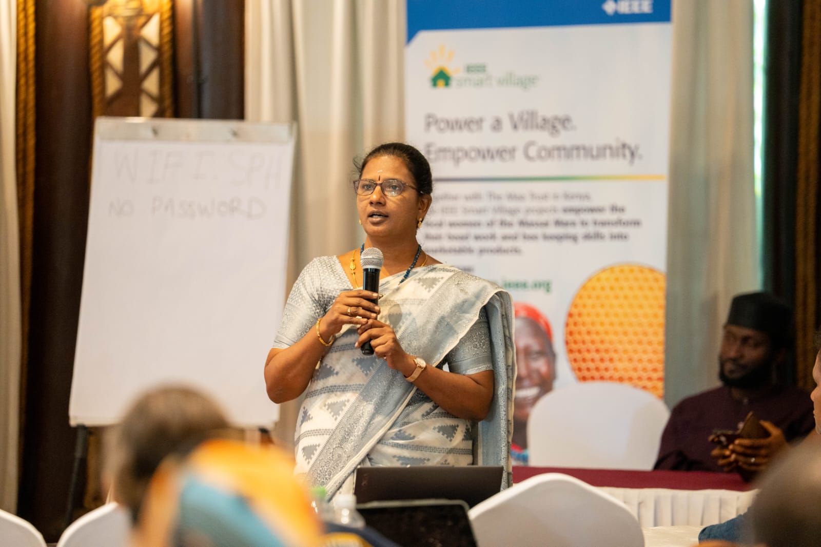 Dr. B. Thanuja speaking into a microphone at a gathering